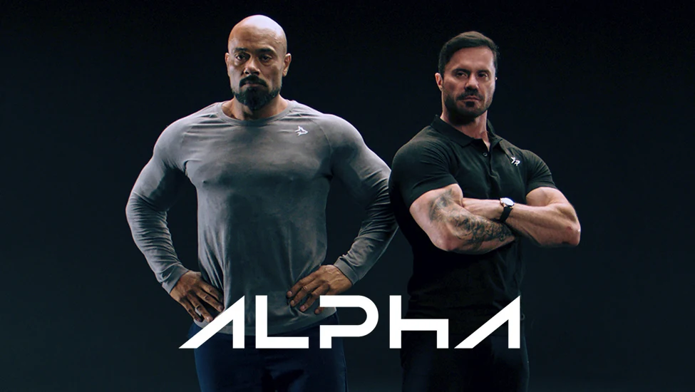 Dois homens vestindo peças da Alpha Co, com o nome da marca em branco.