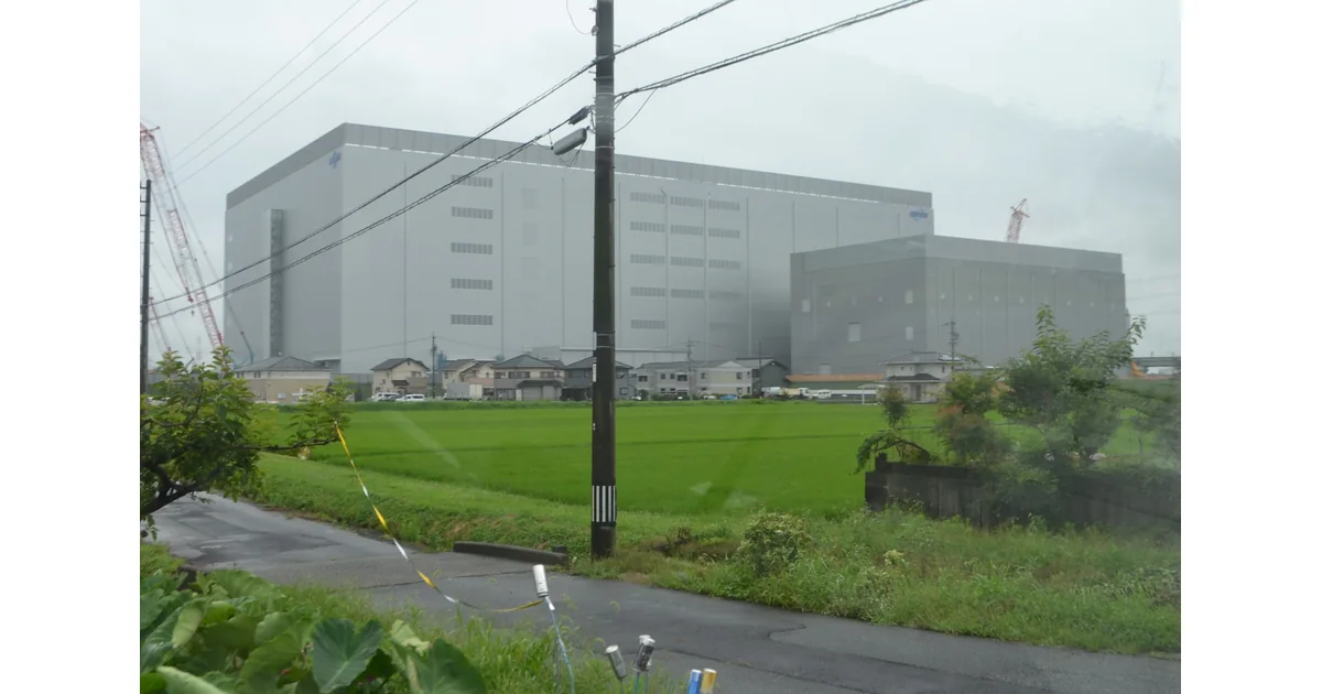 Instalação industrial com edifícios, linhas elétricas e vegetação.
