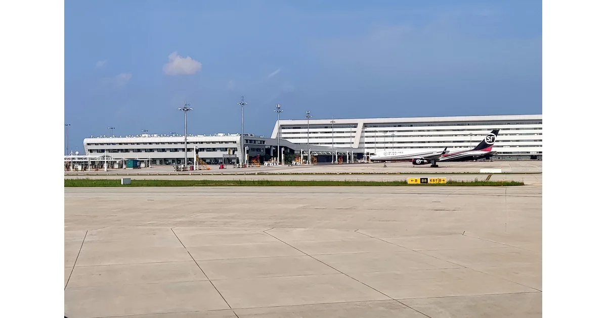 Avião cargueiro estacionado diante de edifícios e pátio aeroportuário.