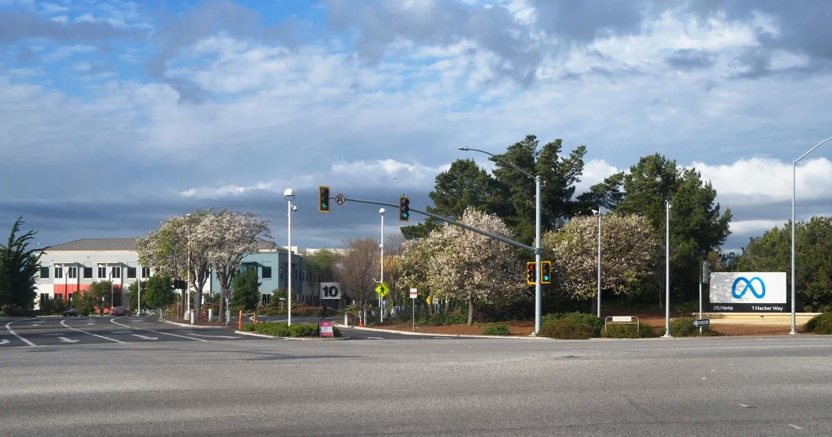 Entrada da sede da Meta em Menlo Park, com edifícios, árvores, cruzamento e placa da empresa