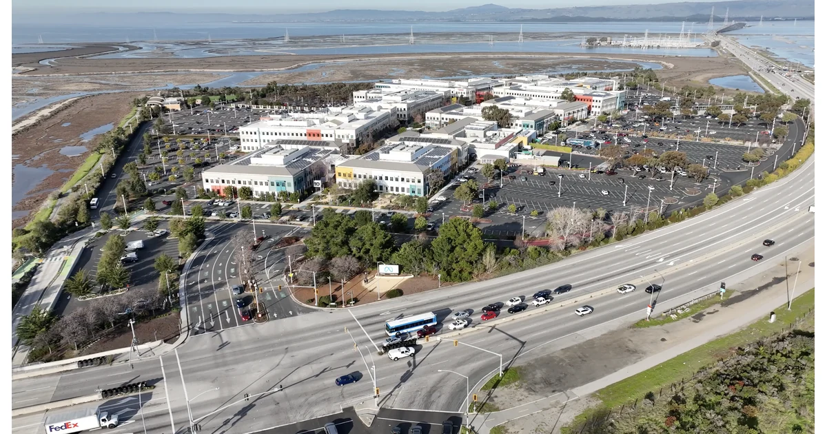 Vista aérea da sede da Meta em Menlo Park, com edifícios, estacionamento, vias e a placa da empresa
