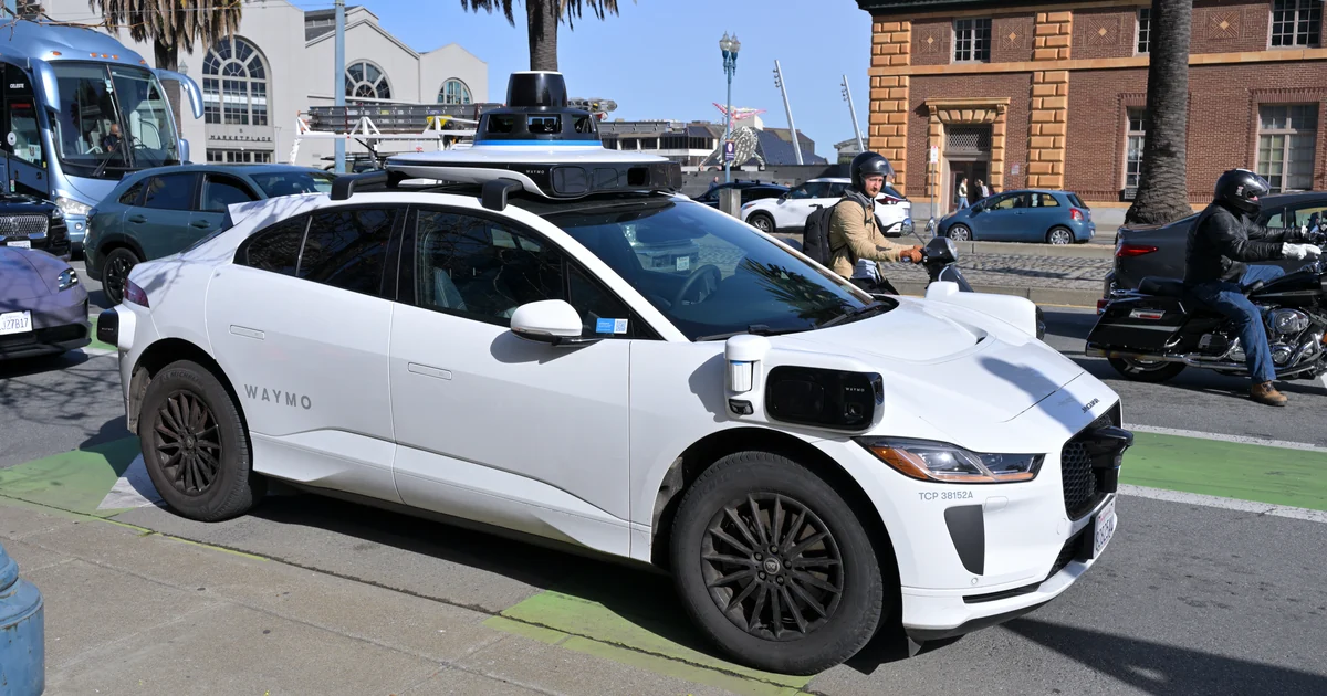 Jaguar branco da Waymo com sensores no teto, circulando no Embarcadero, em São Francisco