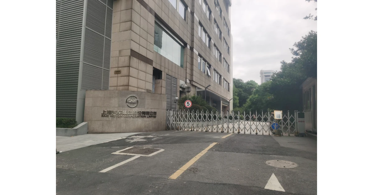 Portão de entrada em prédio comercial, com placa no muro e grade retrátil.