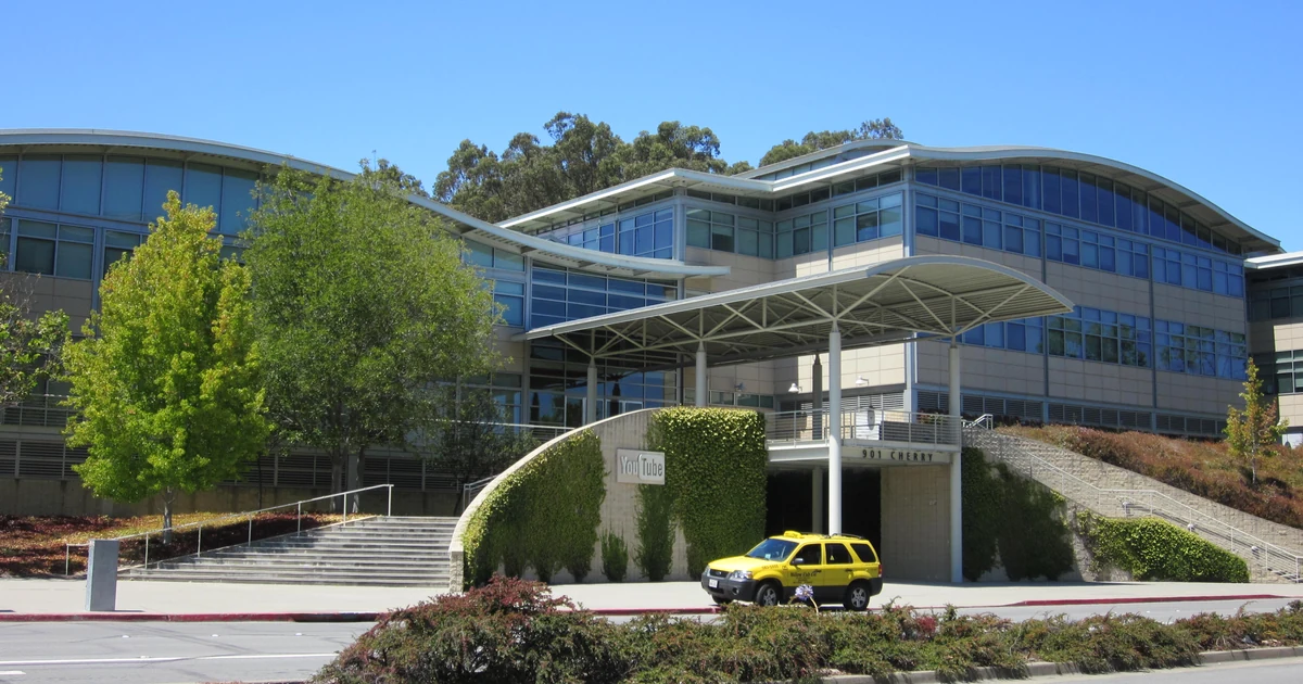 Entrada da sede do YouTube em San Bruno, com o nome da empresa na fachada e um táxi amarelo na rua