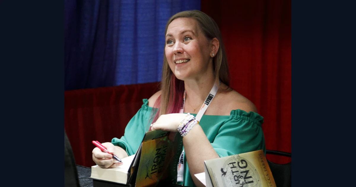 Rebecca Yarros com caneta e livros durante sessão de autógrafos no National Book Festival de 2024
