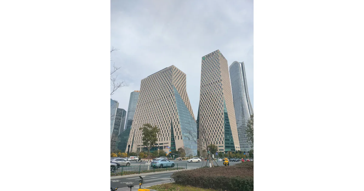 Edifícios altos com janelas, árvores e veículos na avenida.